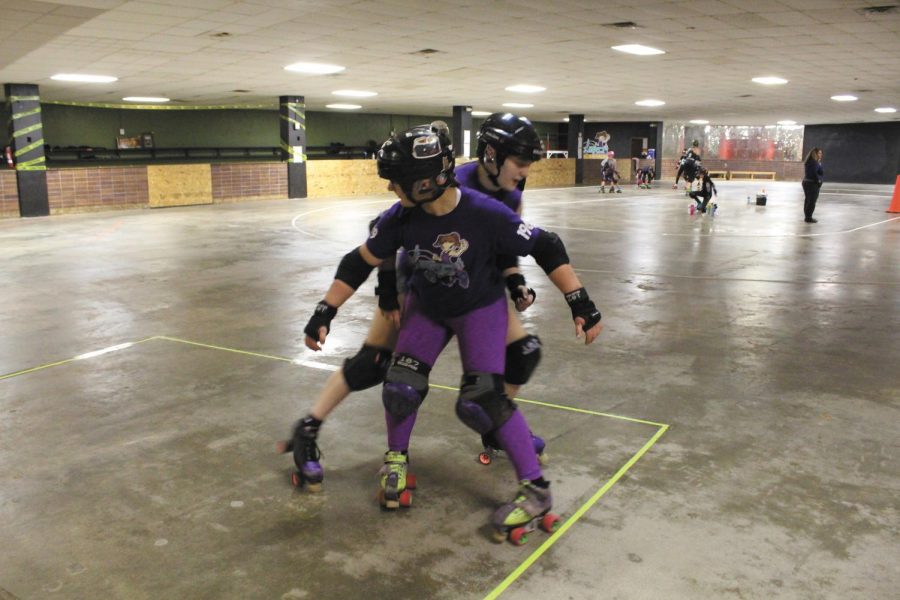 Freshman Caroline Boucher blocks senior Trinity Hettinger from trying to get around her and score a point. “I’ve always loved skating and thought it looked like a great way to take my anger out,” Hettinger said. Photo by McKenzie Gandy.