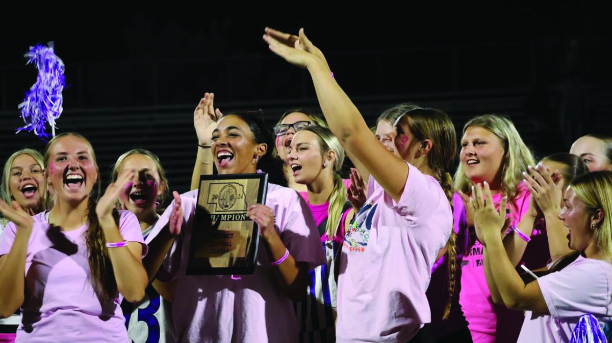 Smiles of winners. (Left) At the October, 8 2024 pep rally, junior Cota Barmore storms the football field with East’s softball team after being honored as district champions. As district champions, the team qualified for the state tournament, and they were recognized for their achievements in front of the whole school. “It was the first time the Bellevue East softball team had won their district, so it was a cool moment for us,” Barmore said. 