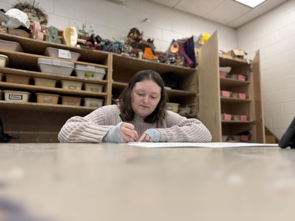  Bold strokes. During their AP Art period, senior Lucky Lewis outlines a drawing of a dinosaur with black marker. Lewis’ first drawing was a dinosaur, but now, they create a variety of artworks for their AP class. “Art is really fun, it's something that I find really helps me express myself,” Lewis said.