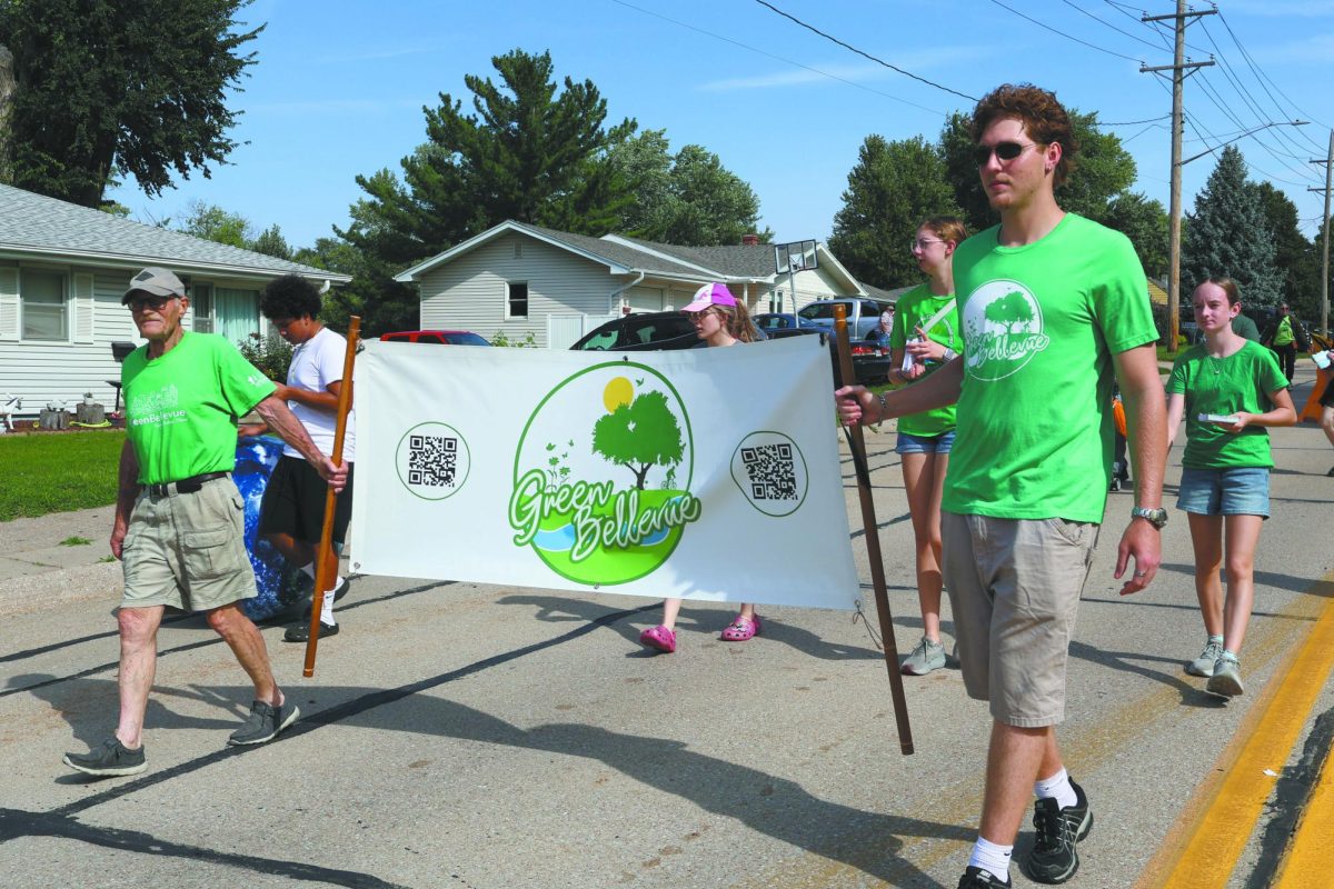 Go green. Walking in the parade with Green Bellevue, sophomore Hannah Kinsey hands out fliers for the club. Green Bellevue, an organization concerned about the environment, advertised volunteer opportunities around the community. “Being a part of the parade was enjoyable as I love to get involved in my community, and this was the perfect way to do so,” Kinsey said. 
