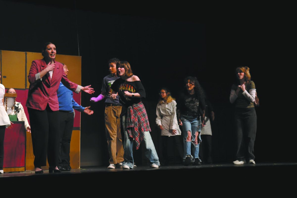 Prove yourself. During the opening act of East’s spring musical, Freaky Friday, on March 14 in the auditorium, Senior Ava Ingraldi [far left] sings proudly as a lead while freshman Mary Maloney [far right] acts to support her performance. Maloney was inspired by Ingraldi's work ethic and leadership throughout the production.. “I'm always trying to show people that I'm the best I can get, which then pushes me to get better,” Ingraldi said.
