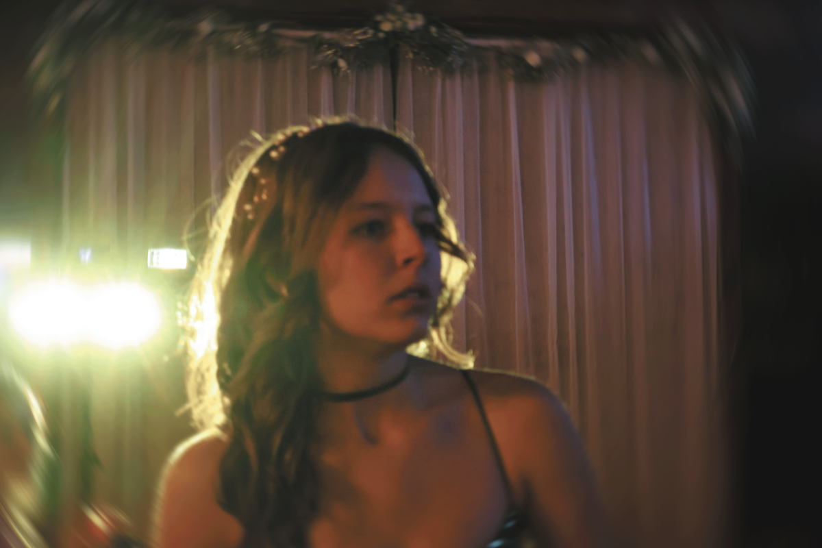 Under the spotlight. Illuminated by the colorful prom lights, senior Trinity Marr accessorizes with her choker and hair adornments. She wanted to match the Atlantis theme but also add touches of her own personal style. “I knew I wanted to do green because it was a color I haven’t done before, and I wanted a sea vibe, so I did that,” Marr said. “And then I feel like my curls—I had waves, like wave curls, so sea vibes.” 